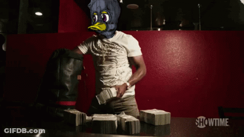A Man In A Duck Mask Stands In Front Of Stacks Of Money With Showtime Written On The Bottom GIF