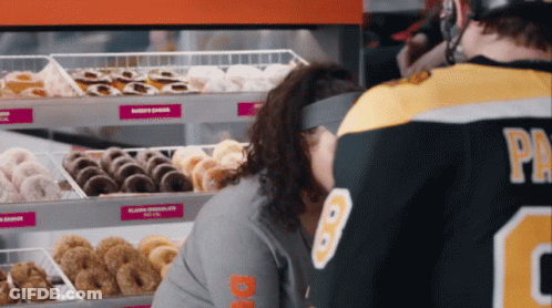 A Man In A Dunkin Donuts Jersey Looks At A Woman 'S Face GIF