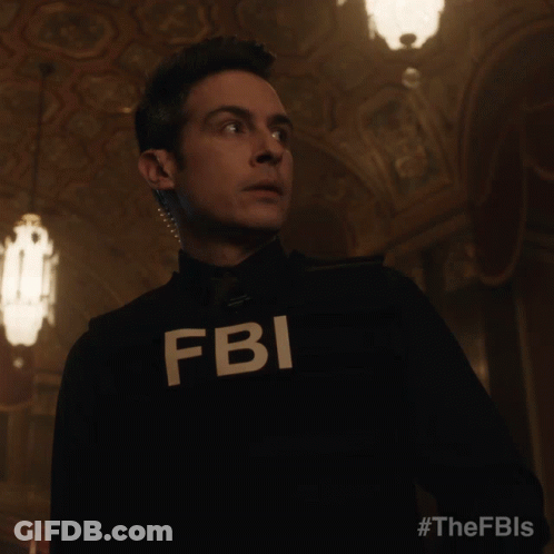 A Man In A Fbi Uniform Stands In A Dark Hallway GIF