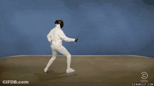 A Man In A Fencing Suit Is Holding A Sword While Another Man In A Fencing Suit Is Dancing . GIF