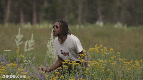 A Man In A Field Of Flowers Wearing A Boy Shirt GIF