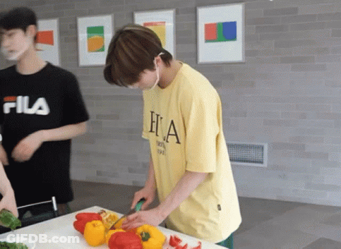A Man In A Fila Shirt Is Cutting Peppers GIF
