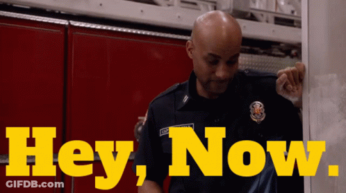A Man In A Firefighter Uniform Is Standing In Front Of A Sign That Says Hey Now GIF