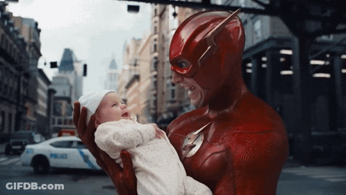 A Man In A Flash Costume Holds A Baby GIF