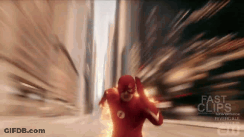 A Man In A Flash Costume Is Running Down A City Street . GIF