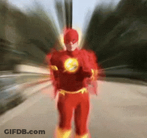 A Man In A Flash Costume Is Running Down A Street . GIF
