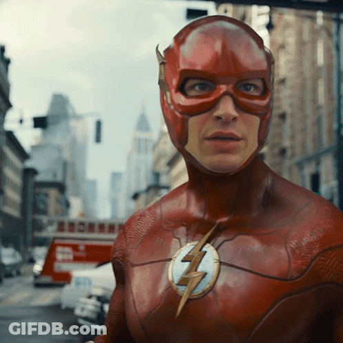 A Man In A Flash Costume Stands In A City Street GIF