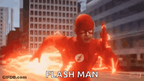 A Man In A Flash Suit Is Running Through A City While Holding A Gun . GIF