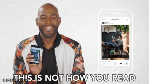 A Man In A Floral Jacket Is Holding A Cell Phone In Front Of A Phone That Says " This Is Not How You Read " GIF