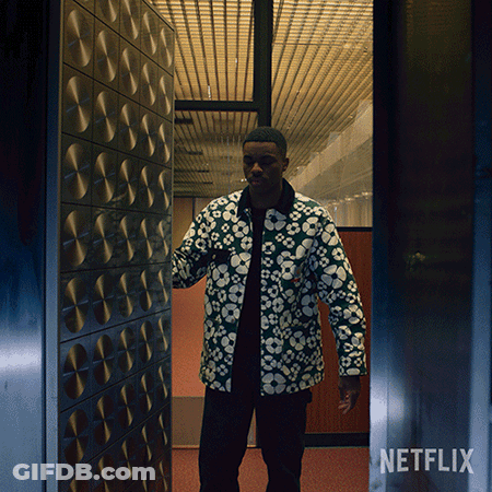 A Man In A Floral Jacket Is Standing In A Doorway With A Netflix Logo On The Bottom GIF