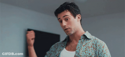 A Man In A Floral Shirt Is Holding His Fist Up GIF