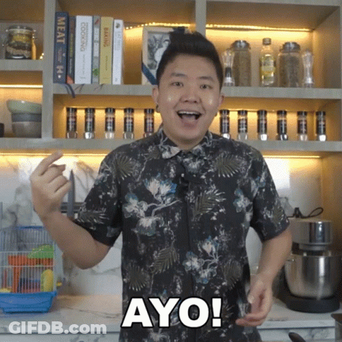 A Man In A Floral Shirt Says Ayo In Front Of A Bookshelf GIF
