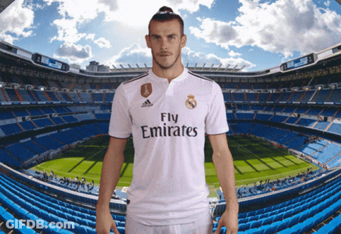 A Man In A Fly Emirates Jersey Stands In Front Of A Soccer Field GIF