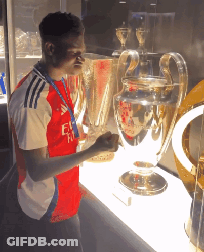 A Man In A Fly Emirates Shirt Holds A Trophy In His Hand GIF