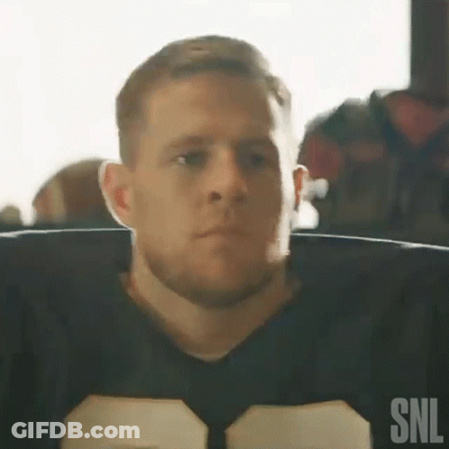 A Man In A Football Uniform Is Sitting In A Chair Looking At The Camera . GIF
