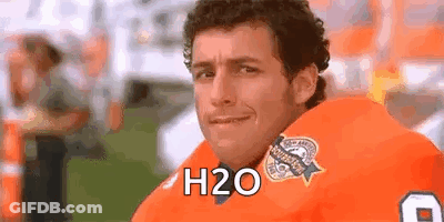 A Man In A Football Uniform Is Sitting On A Field And Smiling At The Camera . GIF