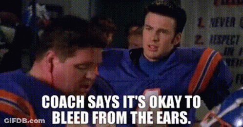 A Man In A Football Uniform Is Talking To Another Man In A Locker Room . GIF