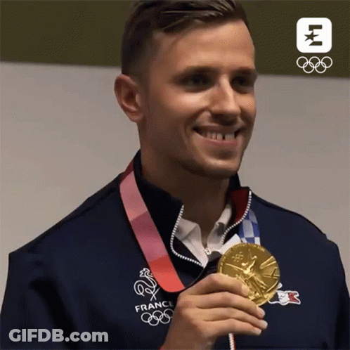 A Man In A France Olympics Jacket Holds A Gold Medal GIF