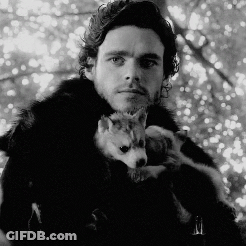 A Man In A Fur Coat Is Holding A Small Dog In His Arms GIF
