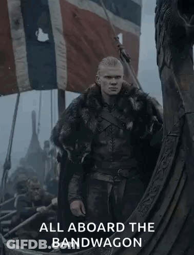 A Man In A Fur Coat Is Standing On A Boat With The Words " All Aboard The Bandwagon " Below Him GIF