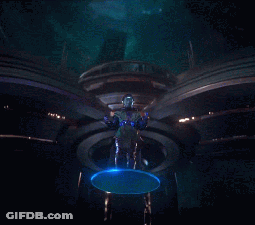 A Man In A Futuristic Costume Is Standing In A Dark Room GIF