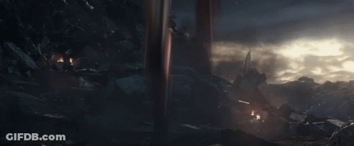 A Man In A Futuristic Suit With Wings Is Standing In The Dark GIF