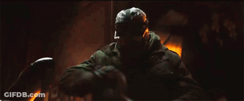 A Man In A Gas Mask Is Holding A Sword In His Hand . GIF