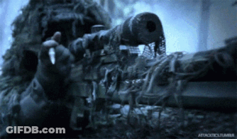 A Man In A Ghillie Suit Is Holding A Sniper Rifle In His Hand GIF