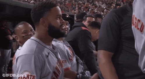 A Man In A Giants Jersey Stands In A Crowd GIF