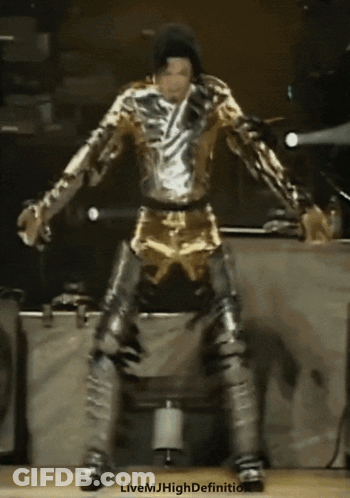 A Man In A Gold And Silver Outfit Is Dancing On Stage GIF