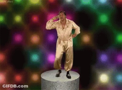 A Man In A Gold Jumpsuit Is Standing On A Podium In Front Of A Colorful Background . GIF