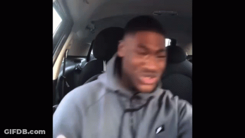 A Man In A Gray Hoodie Is Sitting In The Back Seat Of A Car . GIF