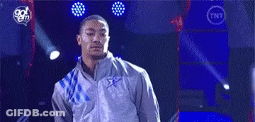 A Man In A Gray Jacket Is Standing On A Stage In Front Of A Blue Background . GIF