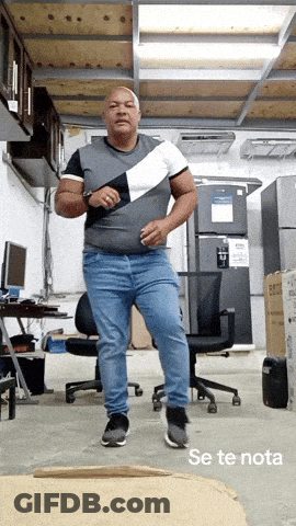 A Man In A Gray Shirt And Blue Jeans Is Dancing In A Room With The Words Se Te Nota Below Him GIF