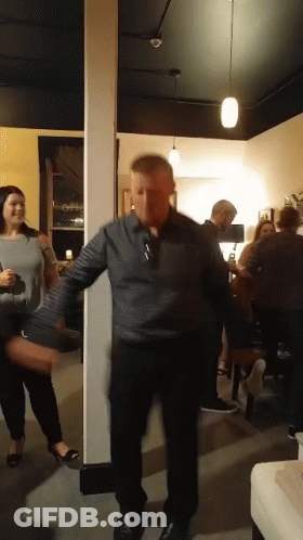 A Man In A Gray Shirt Is Dancing In A Room GIF