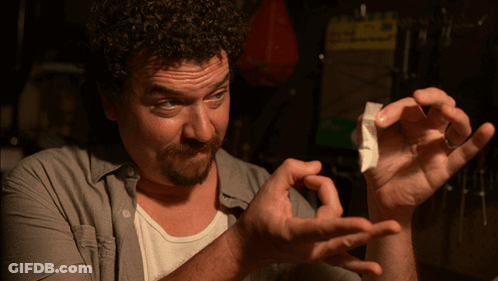 A Man In A Gray Shirt Is Holding A Piece Of Paper In His Hands GIF