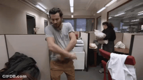 A Man In A Gray Shirt Is Standing In A Cubicle GIF