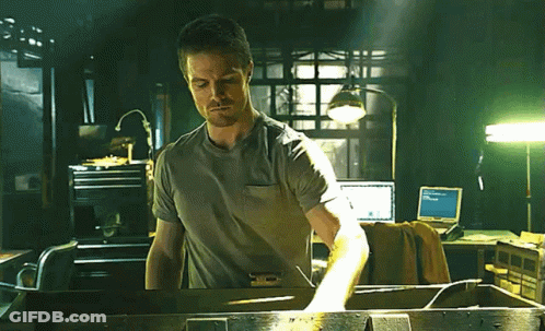 A Man In A Gray Shirt Is Standing In Front Of A Computer Monitor That Says ' Microsoft ' On It GIF