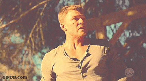 A Man In A Gray Shirt Is Standing In Front Of A Sign That Says Space GIF