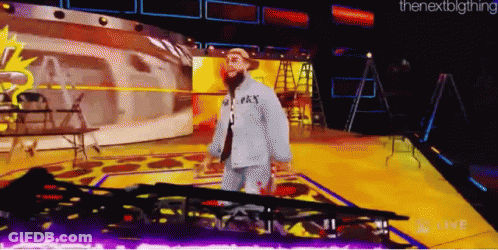 A Man In A Gray Shirt With The Word Pay On It Walks On A Stage GIF