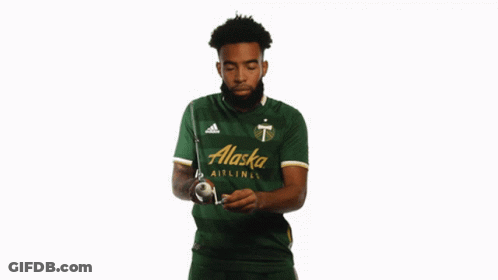 A Man In A Green Alaska Airlines Jersey Holds A Stick GIF