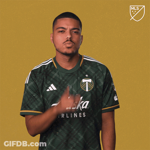 A Man In A Green Alaska Airlines Shirt Holds His Finger To His Mouth GIF