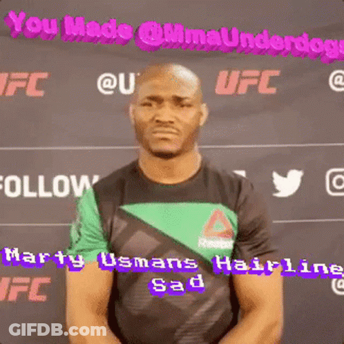 A Man In A Green And Black Shirt Is Standing In Front Of A Sign That Says Ufc GIF