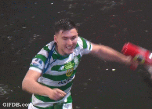 A Man In A Green And White Jersey With A Medal Around His Neck Holds A Red Can GIF