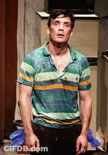 A Man In A Green And Yellow Striped Shirt Stands In Front Of A Refrigerator GIF