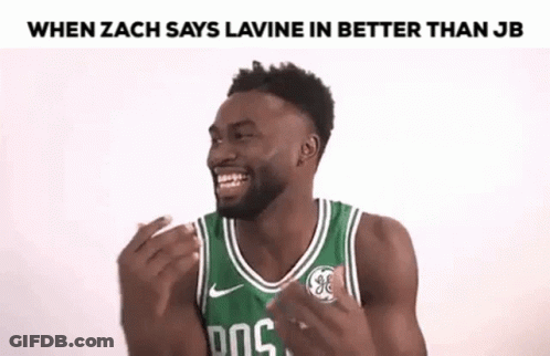 A Man In A Green Basketball Jersey Is Laughing With His Hands Up . GIF