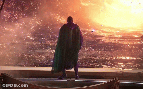 A Man In A Green Cape Is Standing In Front Of A Large Fireball GIF