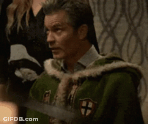 A Man In A Green Coat With A Cross On It Is Holding A Sword And Says I Know GIF
