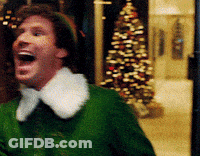 A Man In A Green Elf Costume With A White Collar Is Laughing In Front Of A Christmas Tree GIF