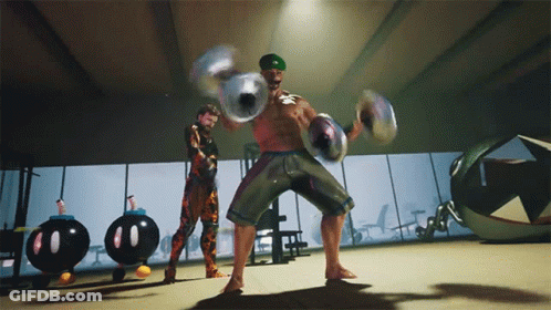 A Man In A Green Hat Holds A Pair Of Dumbbells In A Gym GIF